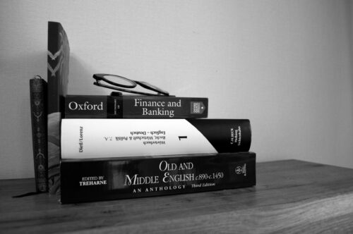 Bücherstapel Stapel von 3 liegenden Büchern, daneben zwei stehende Bücher mit Brille